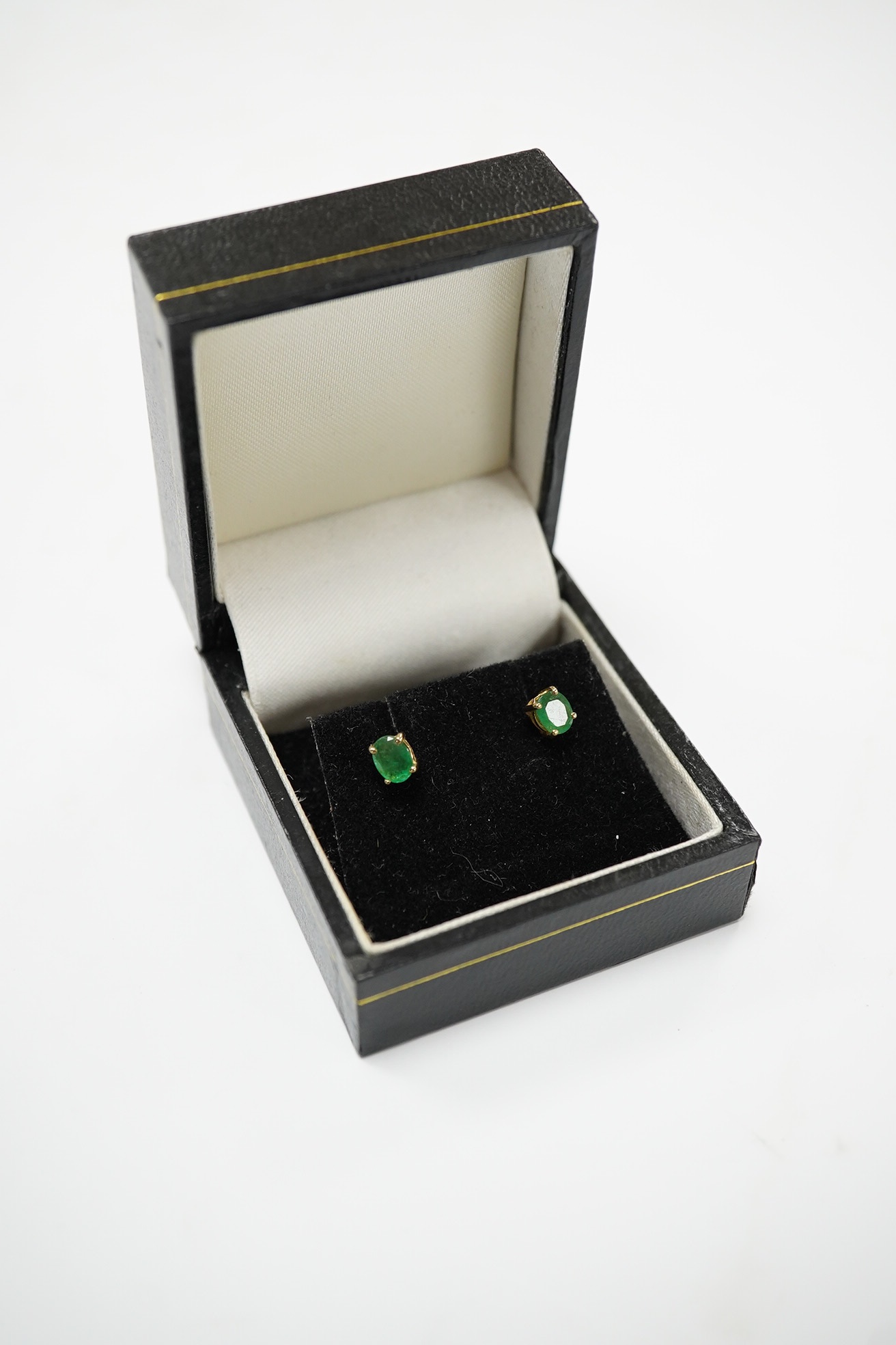 A pair of 9ct and solitaire oval cut emerald set ear studs, gross weight 1.2 grams. Condition - poor to fair